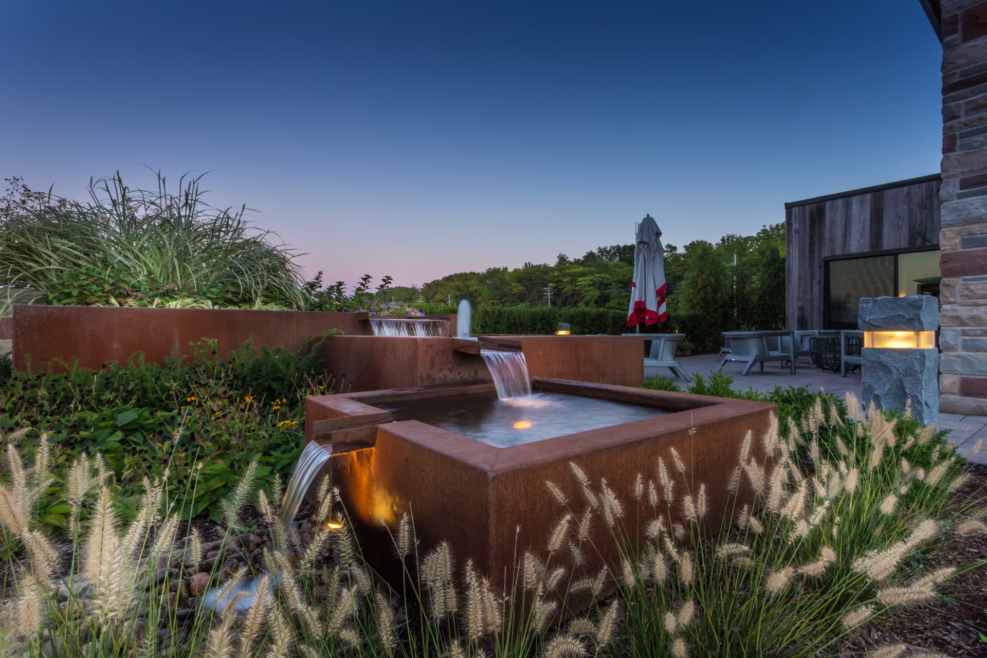 Corten steel water basin with tiered spillways and grasses