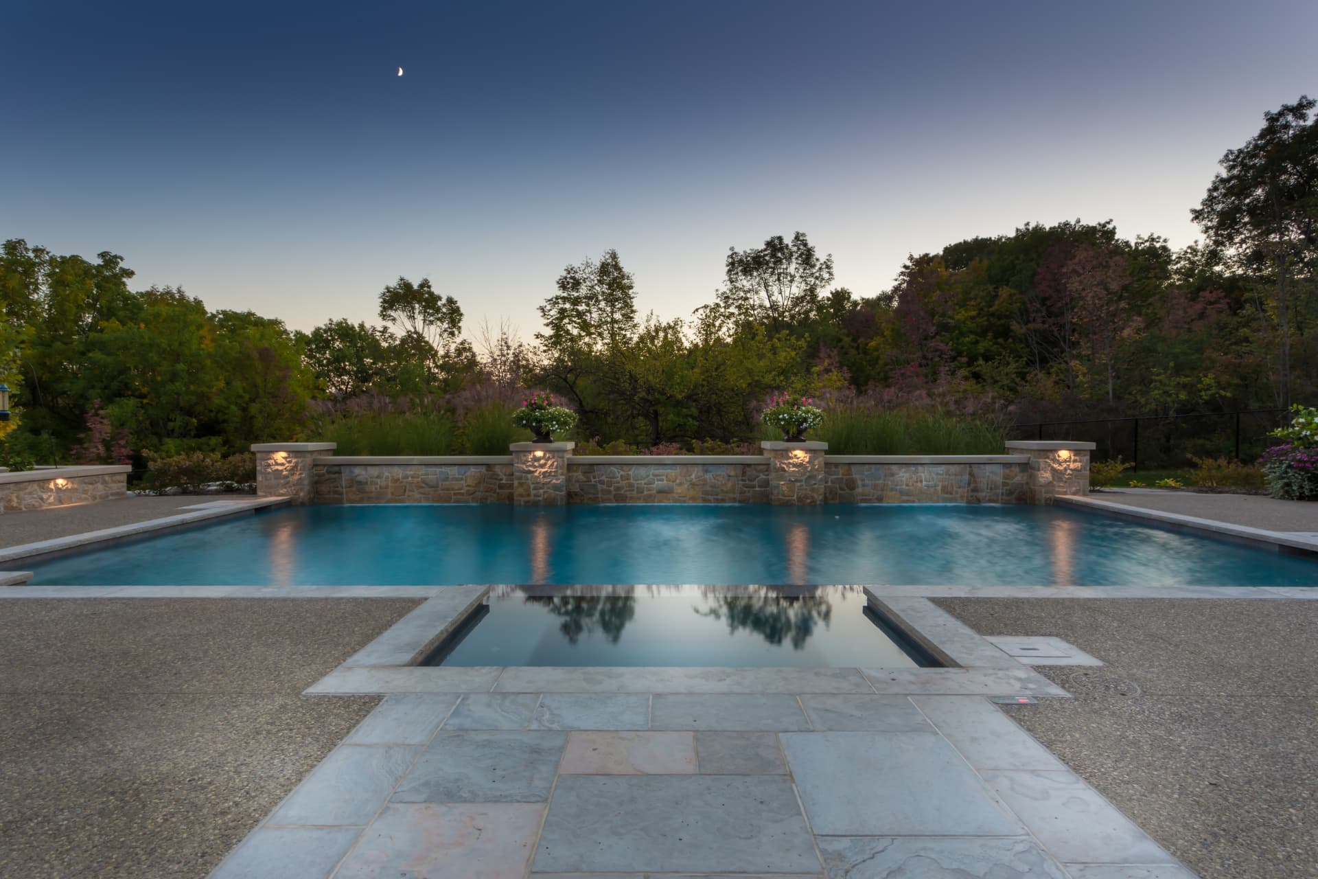 Pool with stone feature wall, lit pillars and integrated spa