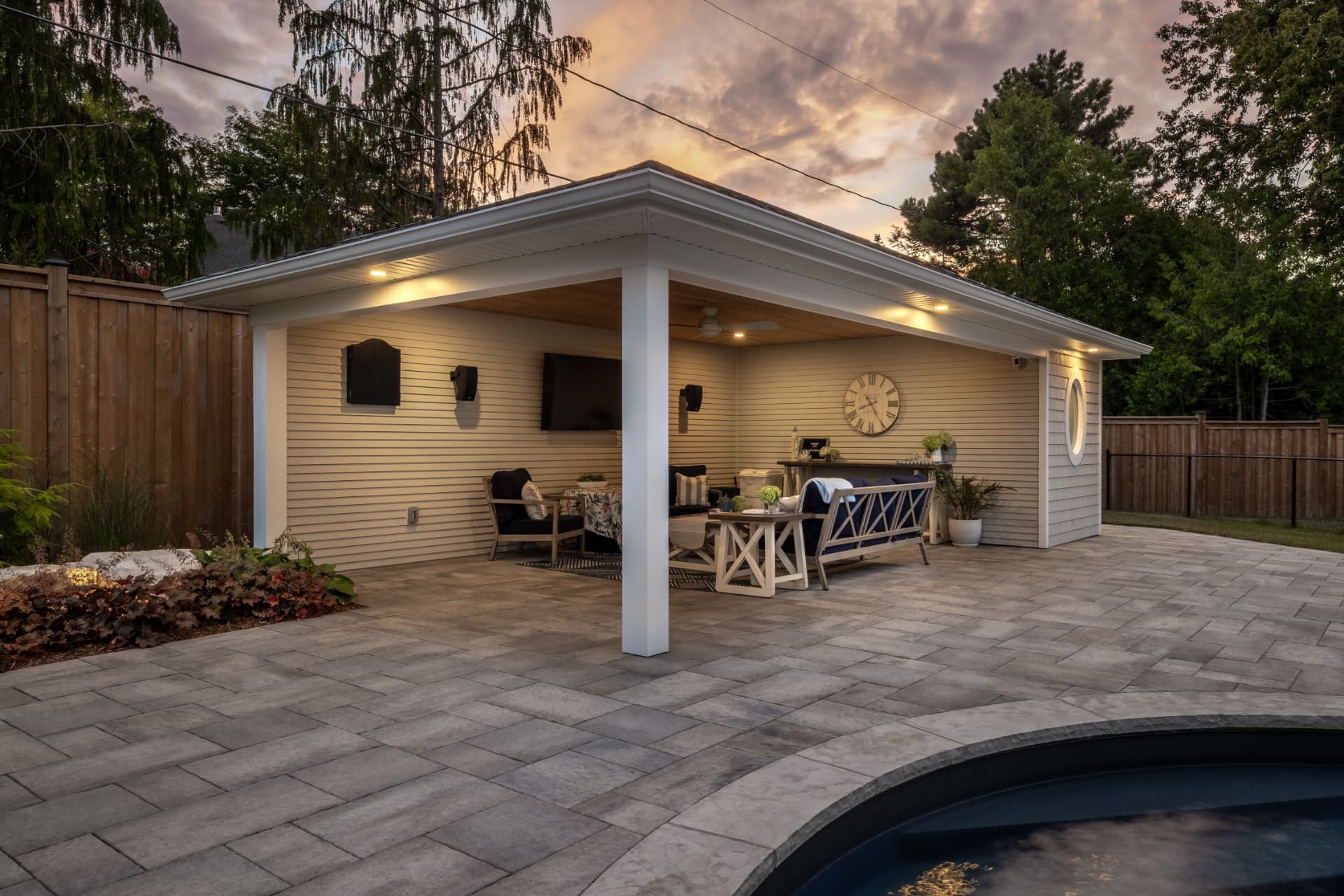 Covered poolside cabana lounge with TV and paver patio