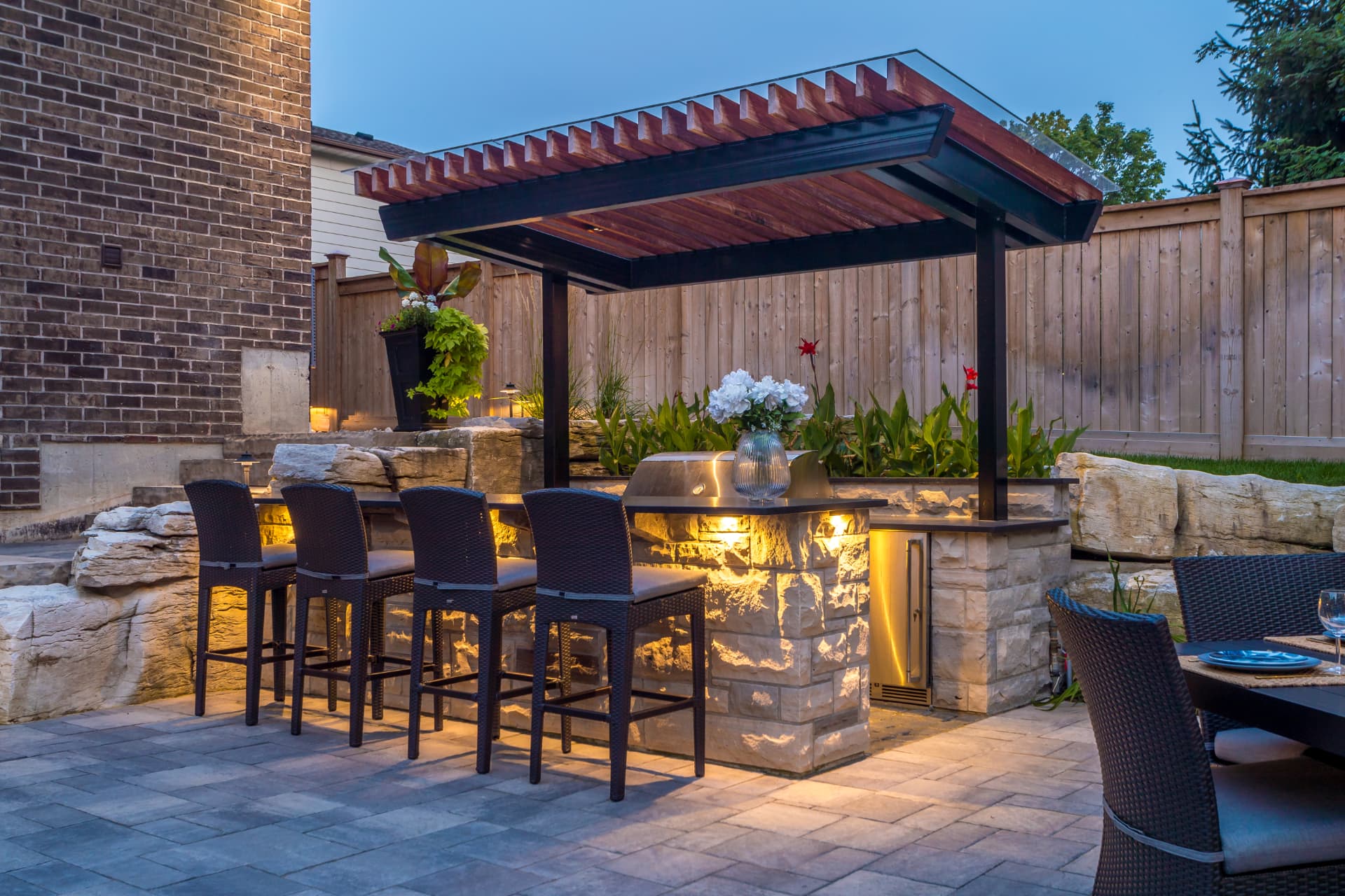 Stone-clad outdoor bar with pergola and integrated lighting