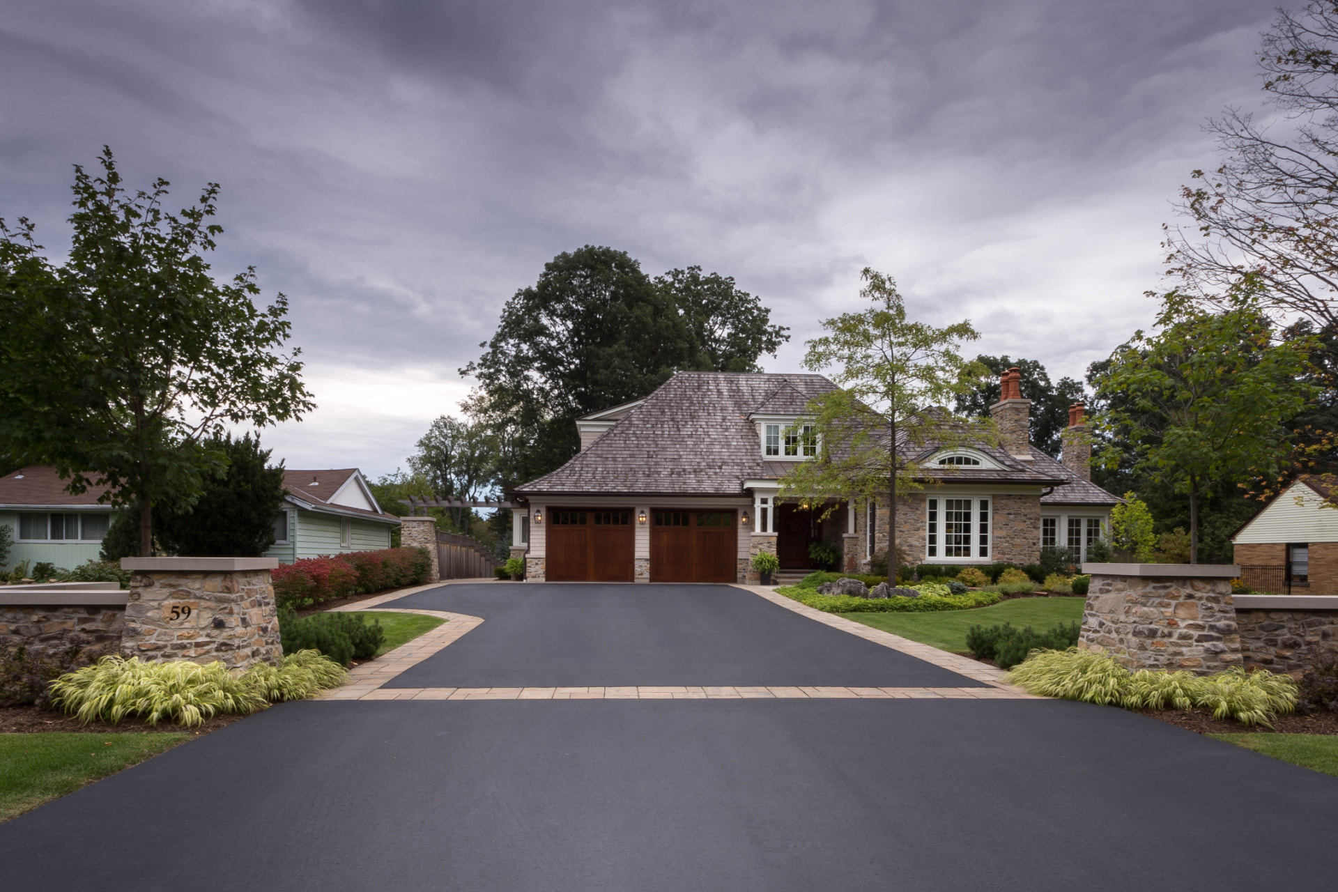 Immaculate front yard, driveway and stone pillars framing a stone estate